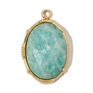 Macro detail of oval light blue natural stone pendant with gold serrated stainless steel edge