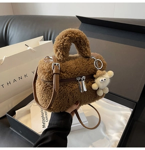 Detail of brown faux shearling crossbody bag with a plush sheep charm in a black gift box