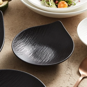 Unique black teardrop-shaped ceramic bowl with textured surface for elegant food serving