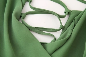 Détail de la robe en mousseline verte avec laçage croisé et texture de tissu délicate