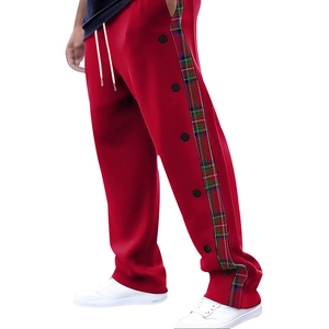 Detail of red joggers featuring side plaid panels and black decorative snap buttons