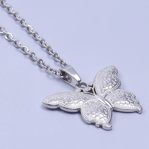 Gros plan du pendentif papillon argenté avec motifs floraux sur chaîne à maillons