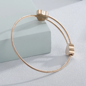 Detail shot of golden heart cable bracelet showing the intricate twisted metal texture