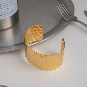 Macro detail of hammered texture on wide 18K gold-plated stainless steel open cuff bracelet
