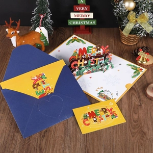3D pop-up Christmas greeting card set with yellow card and blue envelope on festive table