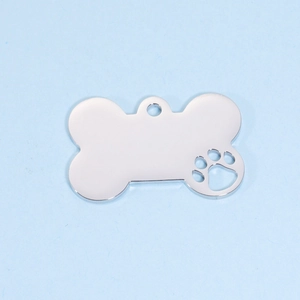 Macro view of bone-shaped stainless steel pet tag with hollow paw print detail