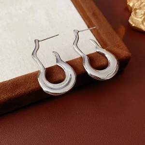 Macro shot of silver polished irregular wave hoop earrings on a velvet display box