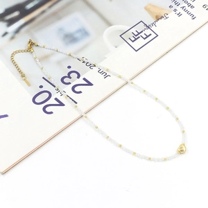 Close-up of a mini crystal beaded necklace with a golden heart pendant and extension chain
