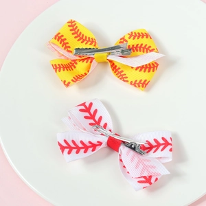 Detail view of bow hair clips with rugby patterns and metal alligator clips on a ceramic plate