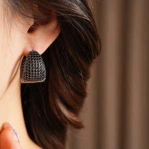 Close-up of elegant C-shaped earrings with micro-pave black zircon worn by a model