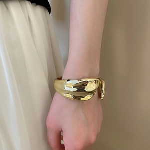 Polished gold irregular cuff bracelet shown on model with white pleated dress