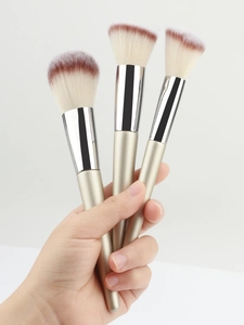Detail of three champagne makeup brushes with soft gradient bristles and metal handles