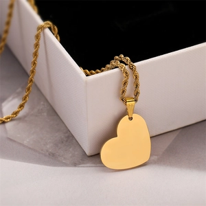 Detail of a polished gold heart pendant with a classic rope chain on a white jewelry box