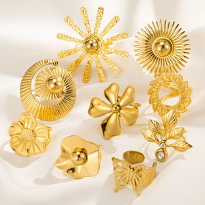 Detailed view of nine gold vintage rings with floral, sun and butterfly motifs on white silk