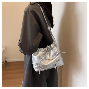 Detail showing the silver chain strap and ribbon bow accents on the stylish crossbody bag