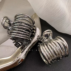 Detail of silver and gunmetal hair clips on a tray with luxury metallic finish