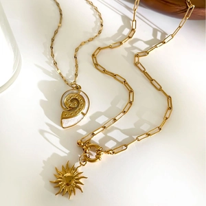Vintage gold sunburst and seashell pendant necklaces on a clean white surface