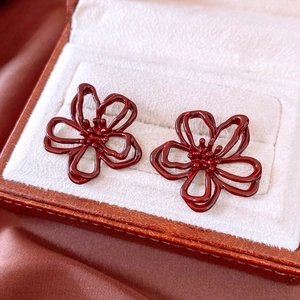 Macro shot of dark red hollow flower earrings displayed in a velvet jewelry box
