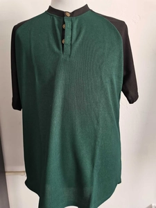 Dettaglio della polo a nido d'ape verde scuro con maniche a contrasto nere e bottoni oro