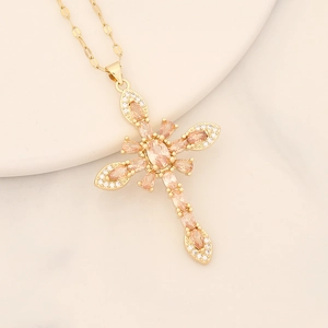 Detail showing gold cross pendant with champagne zircon on a white plate