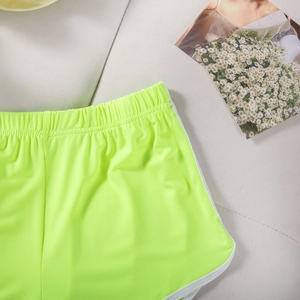 Detailed texture of neon green yoga shorts with white trim on a soft fabric surface