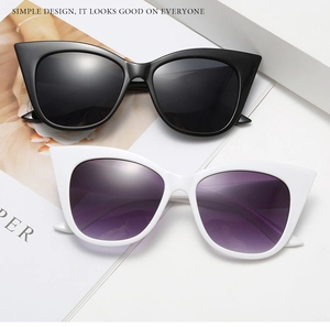 Detail shot of black and white cat-eye sunglasses with gradient lenses on a minimalist stand