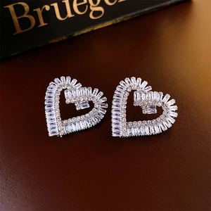 Gros plan de boucles d'oreilles cœur en argent et zircons sur fond de cuir marron