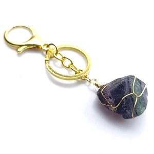 Détail macro du fil d'or fait main enroulé autour d'un porte-clés en fluorite naturelle