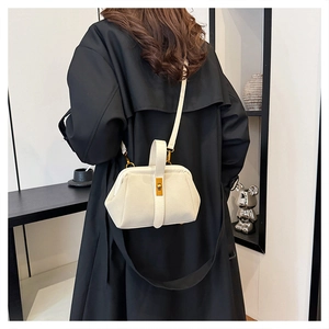 White vintage crossbody bag with metal buckle shown on a model in a long black coat