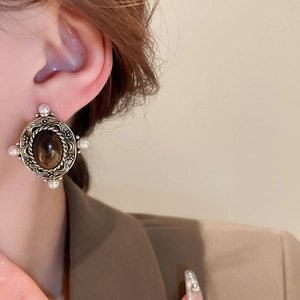 Detailed close-up of retro oval faux tiger eye earrings with vintage gold engraved textures