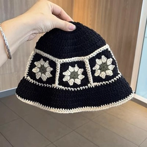 Detail of handmade crochet bucket hat featuring black knit and white daisy flower patterns