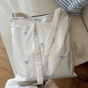 Gros plan sur la broderie de nœud bleu et l'étiquette en tissu du sac cabas blanc