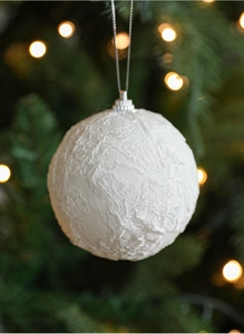 Detail of white lace covered 8cm Christmas foam ball hanging on a pine tree branch