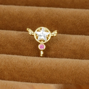 Golden piercing stud with star zircon and pink gemstone wings on brown velvet