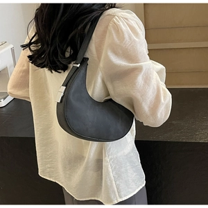 Close-up of black crescent shoulder bag with silver buckle and matte finish texture