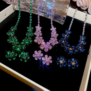 Detailed macro view of zircon flower necklace and earring sets in green, pink, and blue