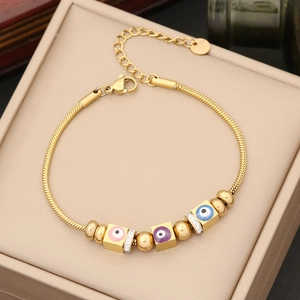 Détail du bracelet chaîne serpent doré avec charms œil maléfique et fermoir mousqueton