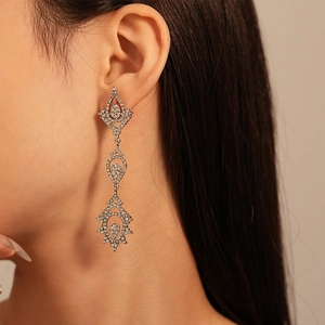 Détail de boucles d'oreilles pendantes de luxe avec strass blancs et aiguille en argent