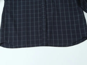 Detail of dark plaid poplin shirt showing the hem, buttonholes and resin button texture