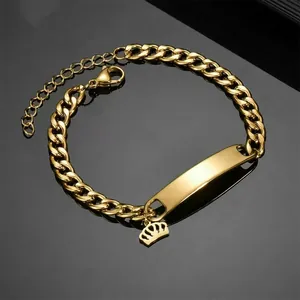 Detail of gold stainless steel Cuban ID bracelet with crown charm on black mirror