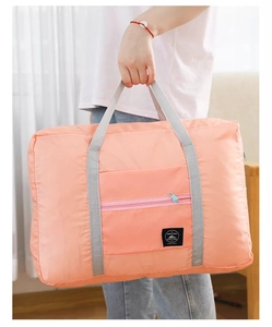 Detail view of large coral pink travel bag with durable gray handles and a woven label