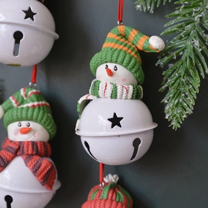Handcrafted Christmas snowman bell ornaments with colorful knit hats on a pine branch