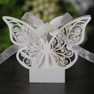 Macro detail of laser-cut white butterfly candy box with elegant ribbon for wedding favors