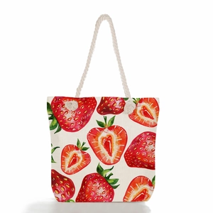 Detail of canvas tote bag showing watercolor strawberry prints and thick rope handles
