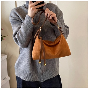 Close-up of caramel suede tote bag with brown leather strap and gold buckle detail
