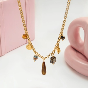 Détail du collier vintage doré avec perles œil de tigre et breloques de pièces de monnaie