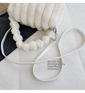 Detail of white plush shoulder bag with striped texture and soft fur ball handle strap