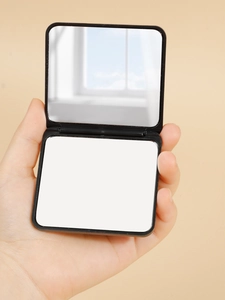 Detail view of a mini black square folding makeup mirror with dual-sided high-definition glass