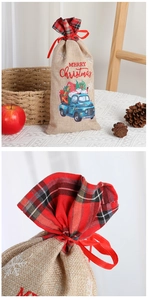 Close-up of linen Christmas gift bag with festive red plaid trim and a blue truck print