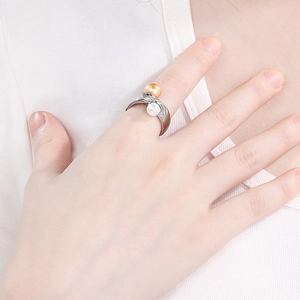 Detailed view of an elegant silver-tone ring with white and champagne pearls on finger